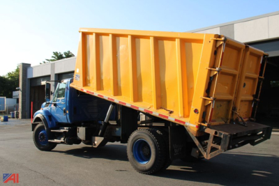 Dump truck 2011 International WorkStar 7400 side view with yellow dump bed raised on blue cab at a dealership