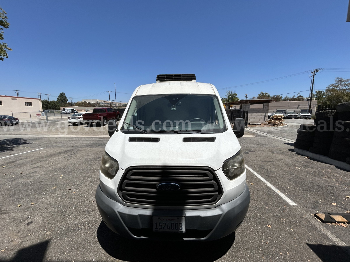Ford Transit refrigeration truck front view showing grille and cab in service; license plate visible; roof refrigeration unit on top.