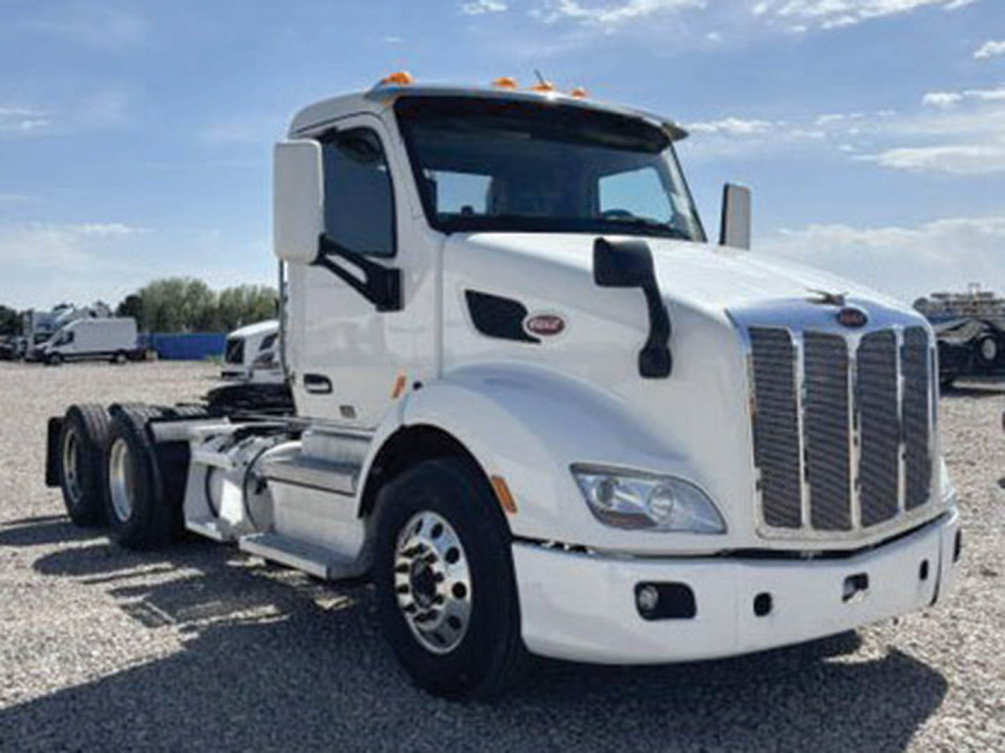 Peterbilt 579 daycab tractor truck in white, front view showing grille, bumper, headlights, and side mirrors.
