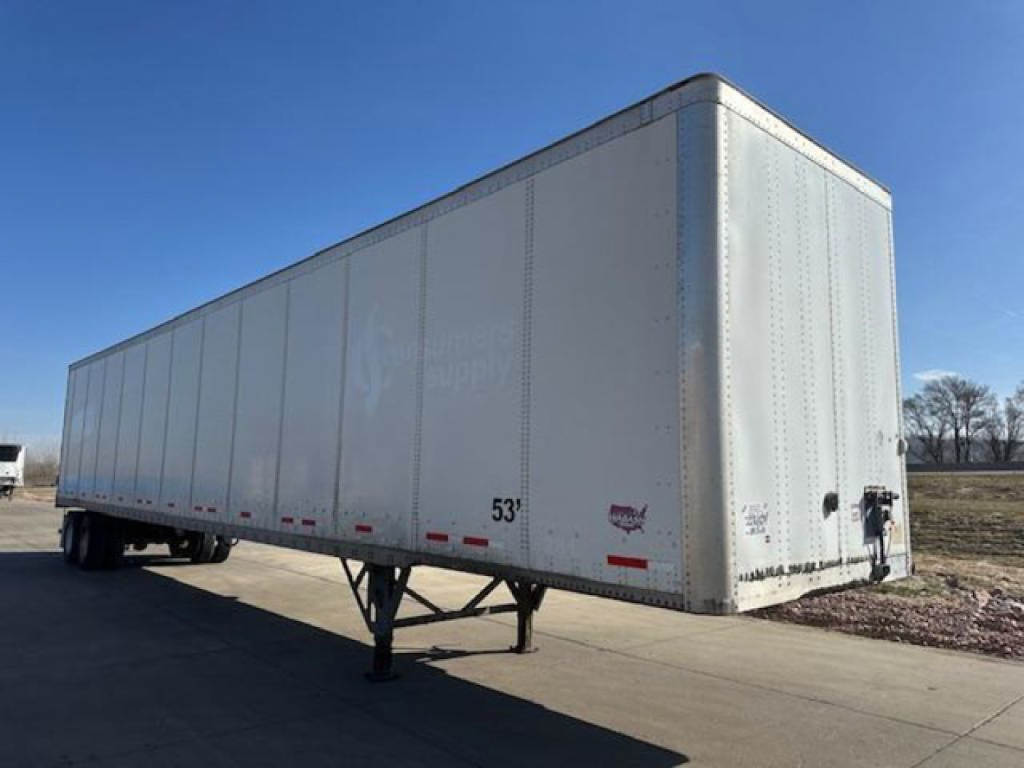 Trailer side view showing a white 53' Wabash van trailer with landing gear and rear doors.