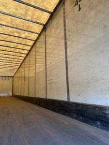 Trailer interior showing sidewall and roof ribs of a Wabash van trailer; wooden floor and metal walls with vertical seams.