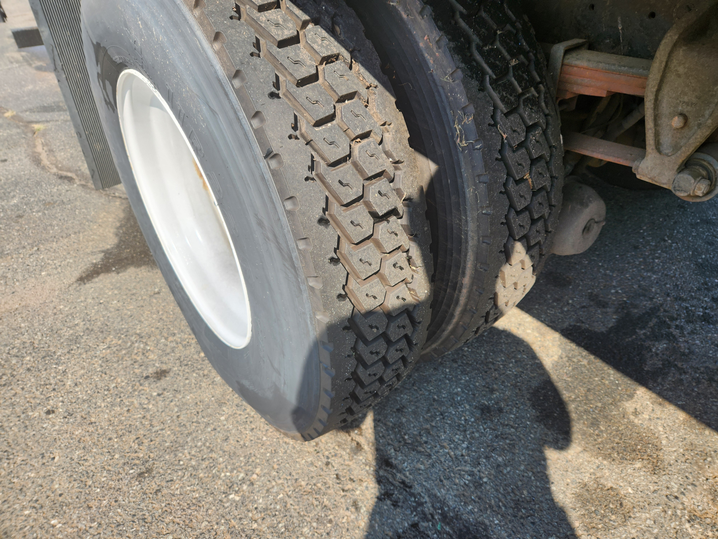 Truck wheel and dual rear tires for a 2018 Hino 338 drivetrain showing heavy tread and suspension components.