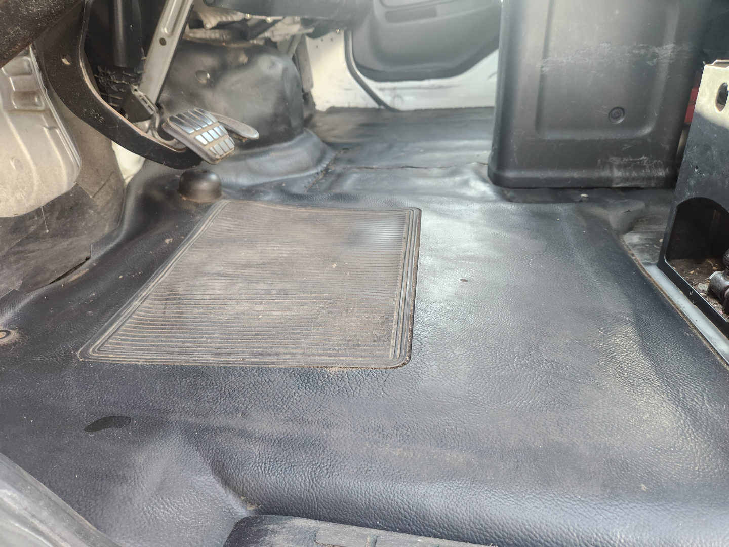 Hino 338 cab interior image showing clutch pedal and floor area near driver seat with bare metal and rubber mat.