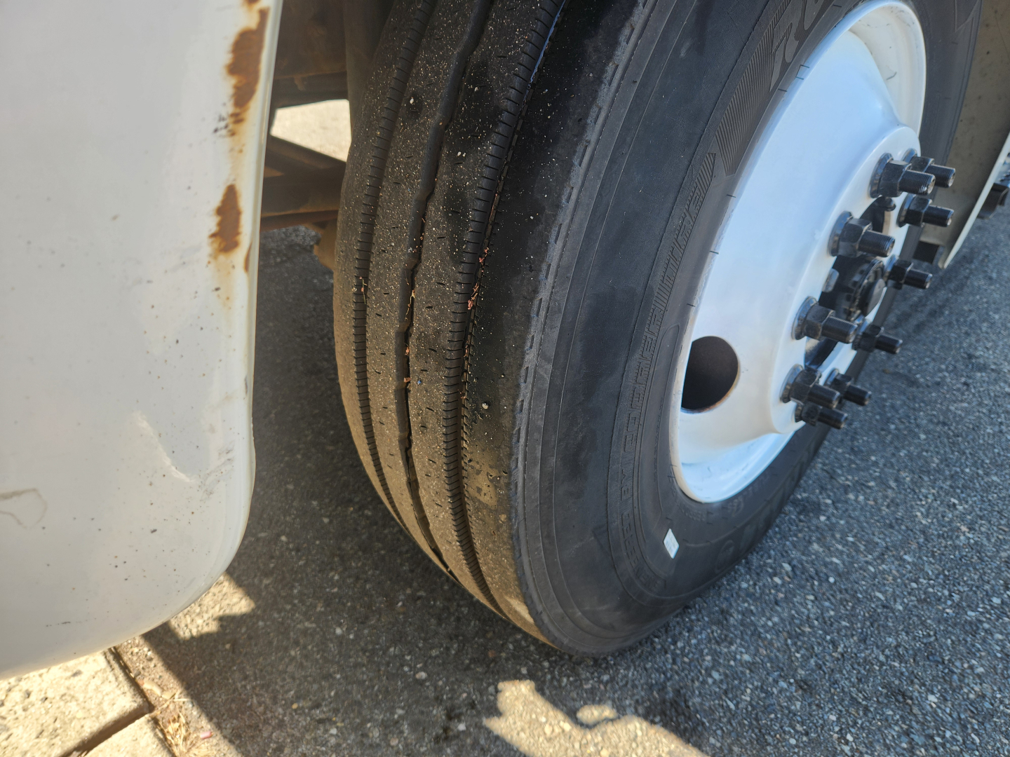 Wheel and front tire close-up on a Hino 338 box truck showing dual rear tires and wheel hub with lug nuts.