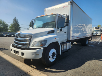 Box truck 2018 Hino 338 de-rate in a parking lot, white cab and box, VIN 5PVNV8JV7J4S57960 visible on listing, front grille with Hino emblem.