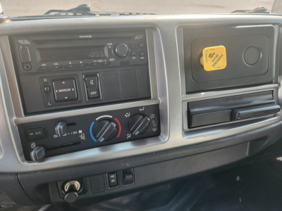 Dashboard area of 2018 Hino 338 cab showing climate controls, radio, and yellow maintenance cap.