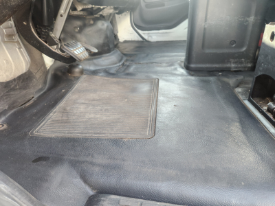 Hino 338 cab interior image showing clutch pedal and floor area near driver seat with bare metal and rubber mat.