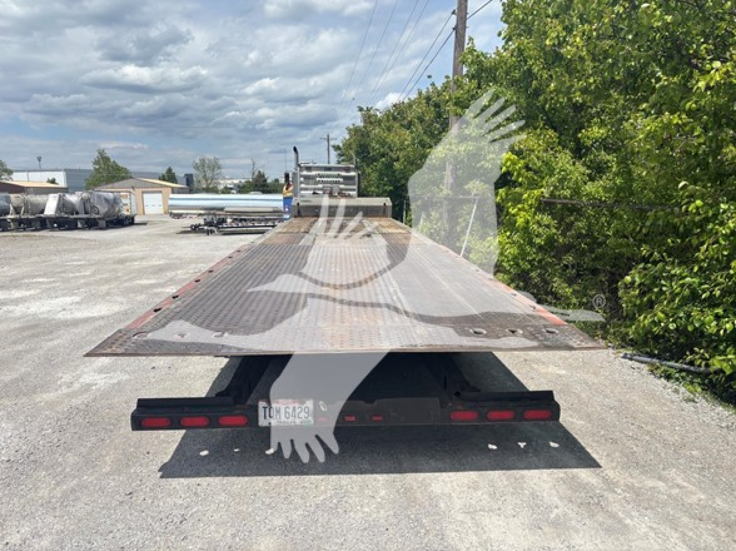 Landoll 950C trailer rear view showing flatbed with ramp, rear lights, and license plate area; VIN sticker visible on side.