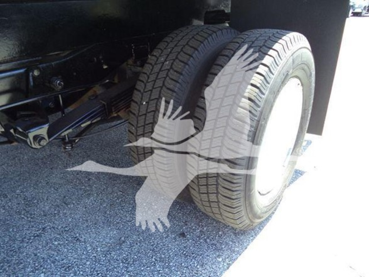 Ford E450 chassis with dual rear wheels and suspension components visible; tire treads and wheel rims shown under vehicle.
