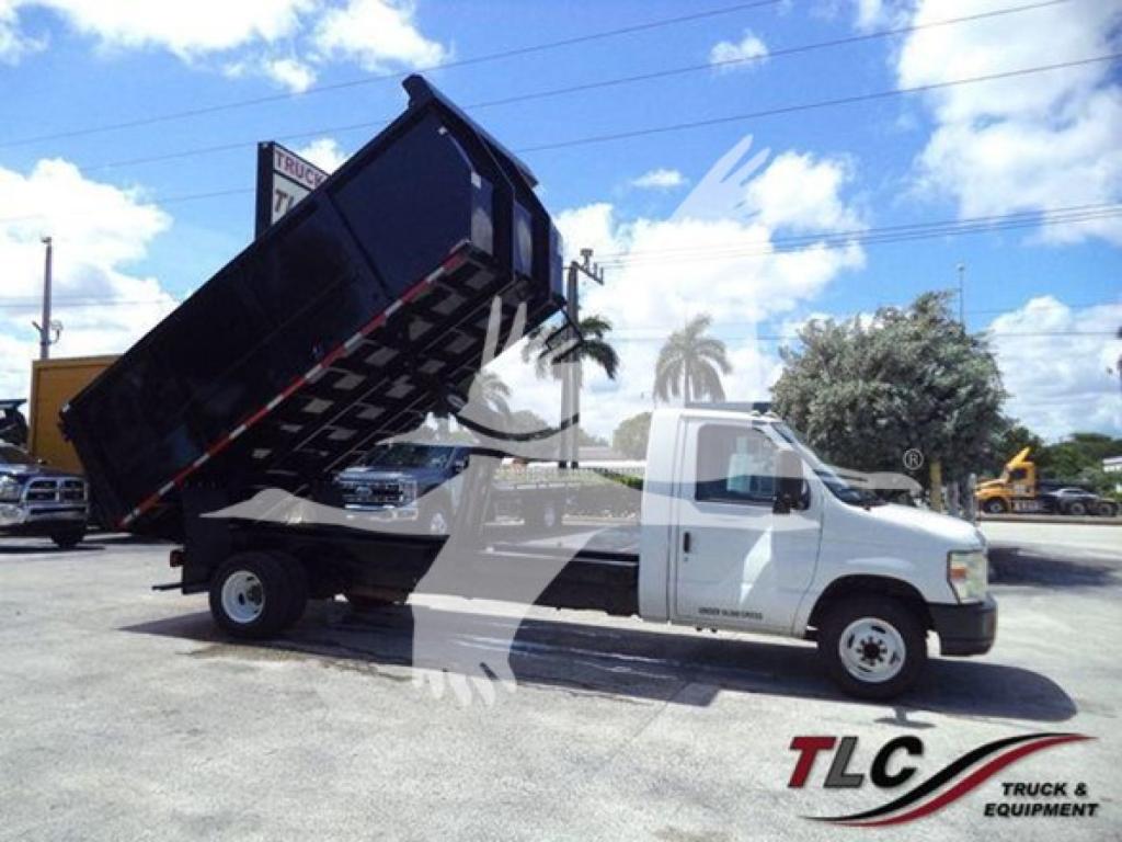 Ford E-450 dump truck with hydraulic bed raised, white cab and black dump body.