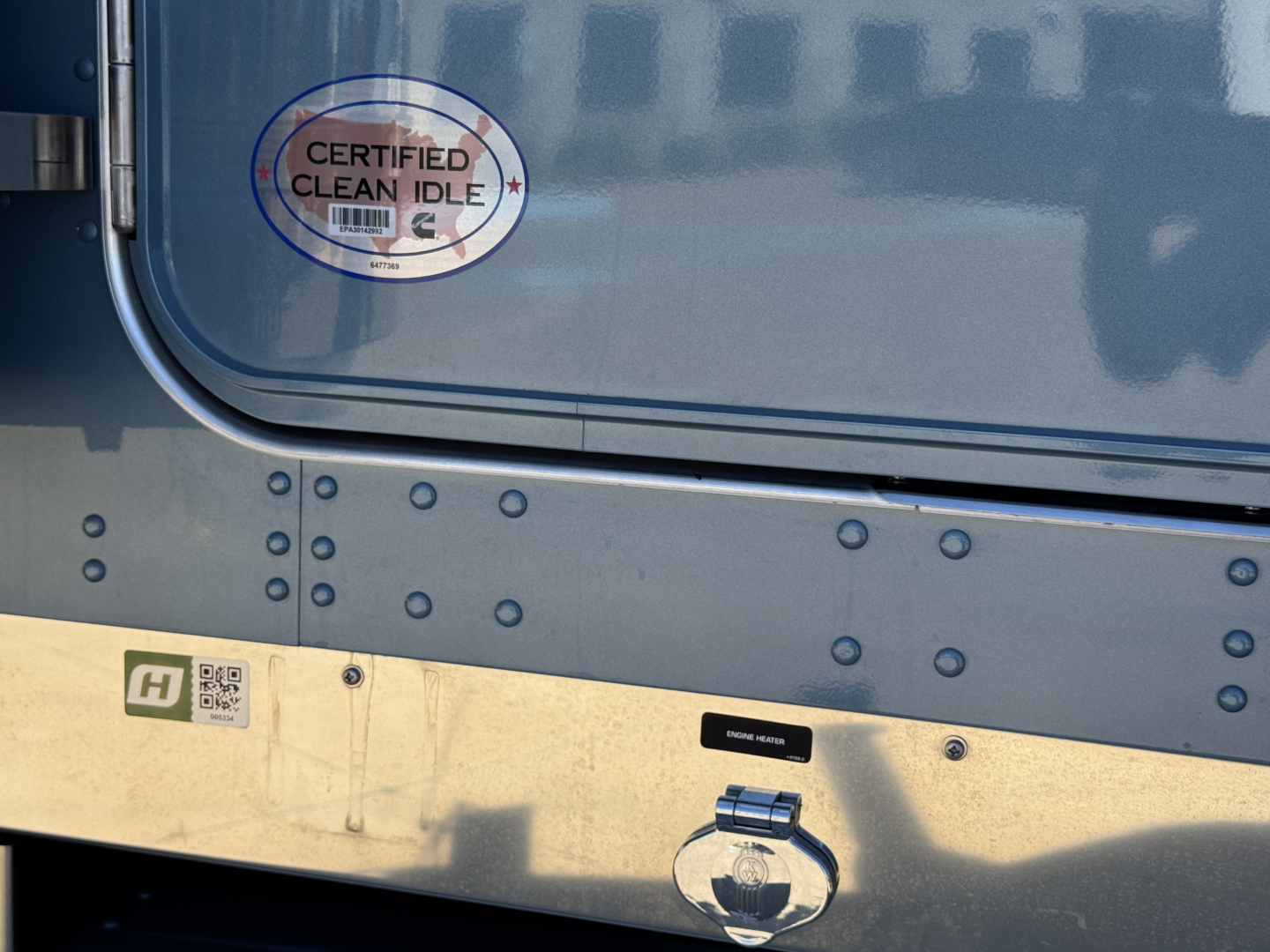 Kenworth W900L side view showing certified clean idle sticker and fuel cap in engine bay area.