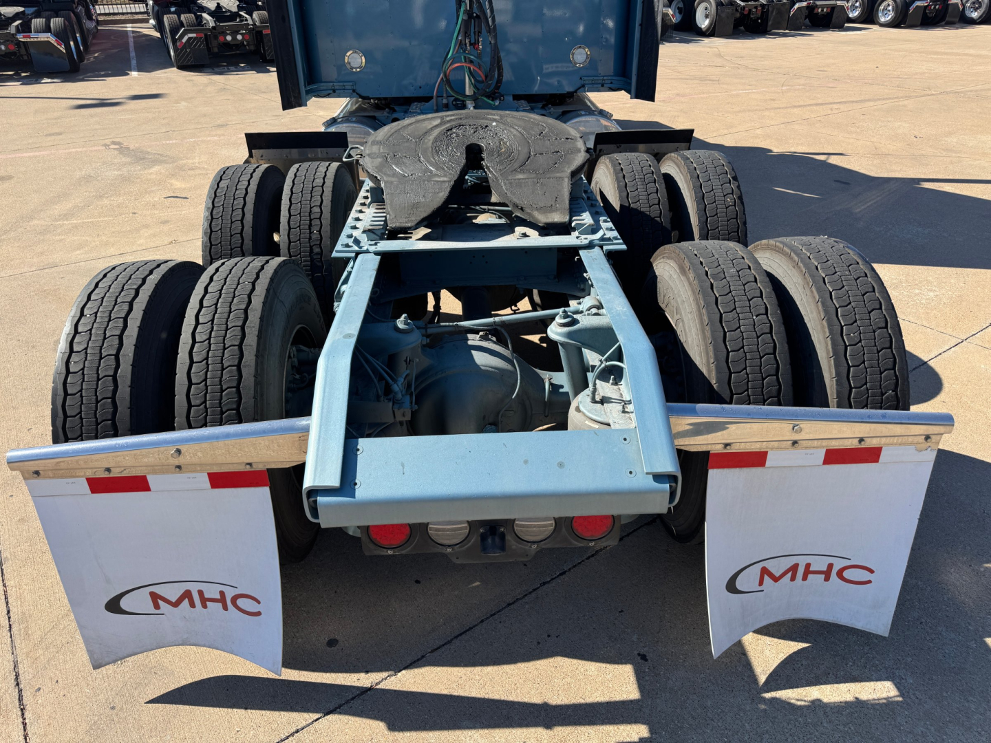 Kenworth W900L rear chassis showing dual rear axles and fifth wheel hitch with mudflaps labeled MHC.