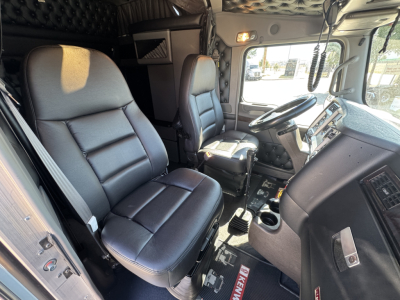 Kenworth W900L truck interior showing driver and passenger seats, dashboard, steering wheel, and center console.