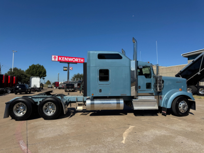 Kenworth W900L conventional sleeper truck side profile showing blue cab, chrome exhaust stacks, and tandem rear axles.