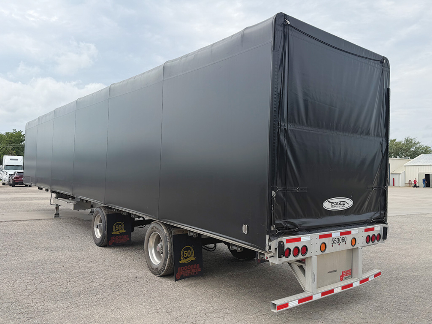 Doonan aluminum curtainside flatbed trailer in a parking lot, side view with covered curtain sides and rear lights visible.