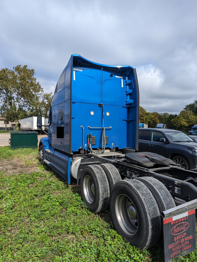 Peterbilt 579 tractor rear view showing blue cab and dual rear axle with fifth wheel hitch.