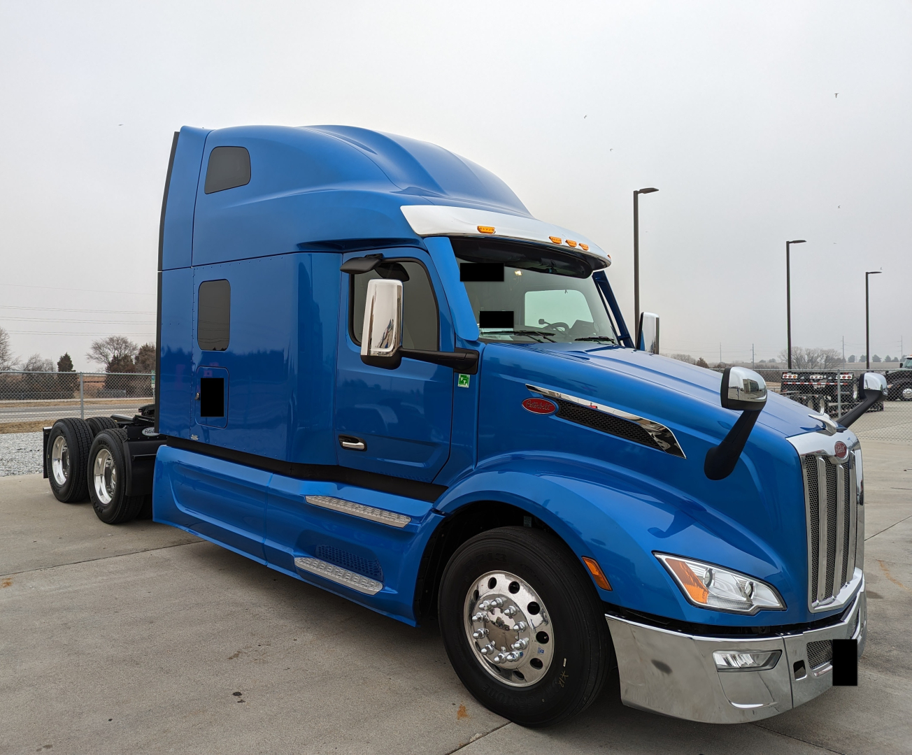 Peterbilt 579 long-hood tractor in blue, side view showing sleeper cab and chrome accents.