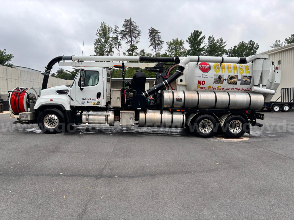 Waste grease vacuum truck with long hose boom and stainless tank showing  Stop Grease signage and dual rear axles.