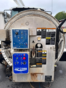 Back view of Freightliner 114 SD vacuum truck rear equipment panel with blue control box labeled Vactor 2100