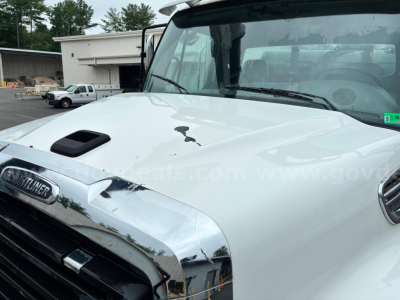 Front view of a 2013 Freightliner 114SD hood and windshield with a damaged hood and chrome grille area visible.