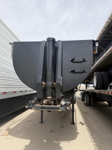 Frontal view of a 2025 Brazos 34' steel frameless rock end dump trailer with high lift gate showing the hitch and hydraulic cylinders.