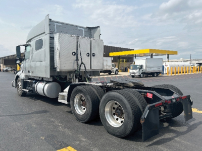 Volvo VNL truck tractor with sleeper cab and rear dual axles, chrome fuel tanks, and flatbed chassis.