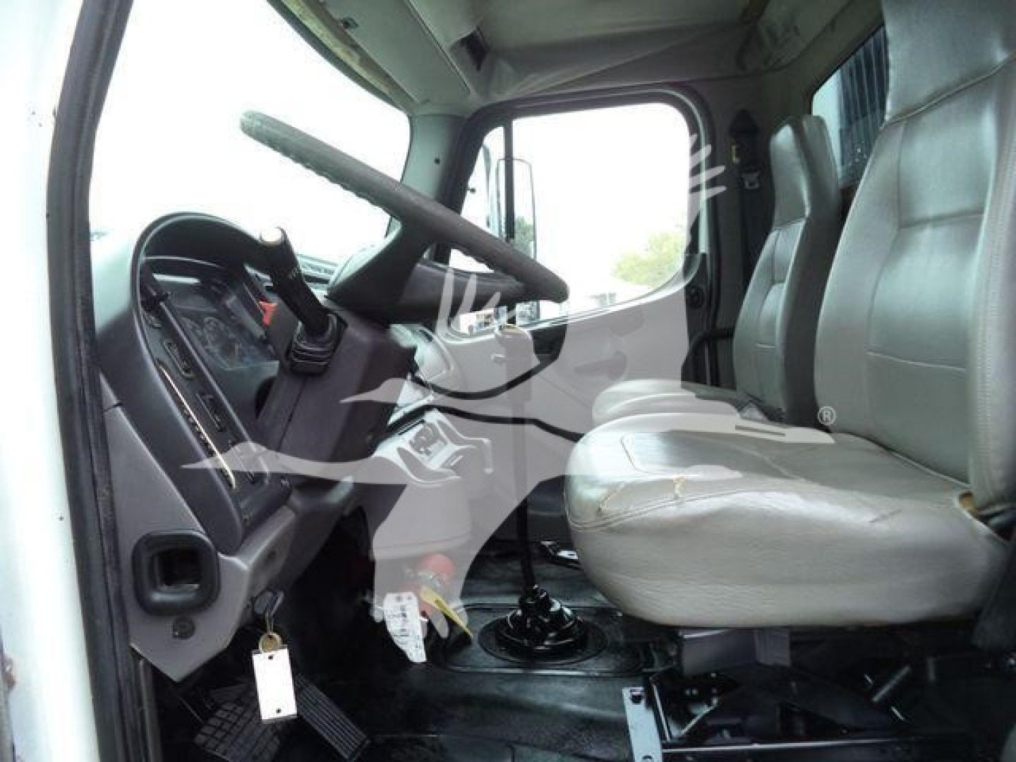 Cab interior of a 2006 Freightliner M2 106 showing steering wheel, driver seat, and gear shift.