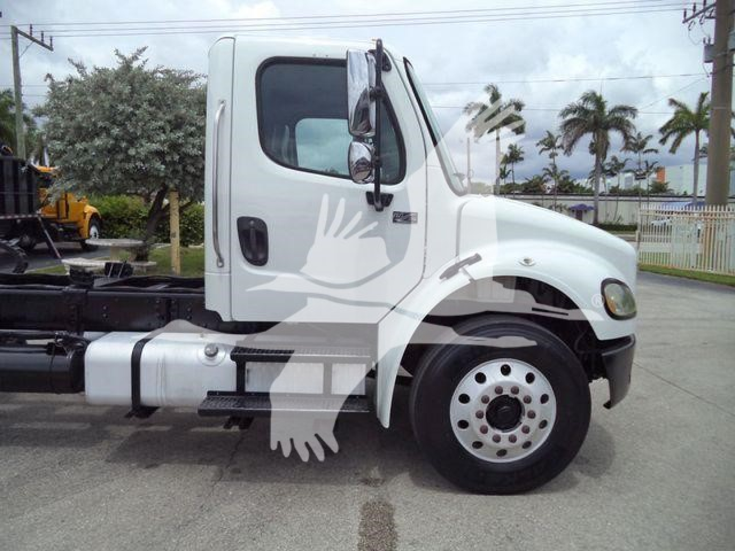 Truck cab side view of a white 2006 Freightliner M2 106 rolloff truck showing cab door, mirror, front wheel, and chassis frame.