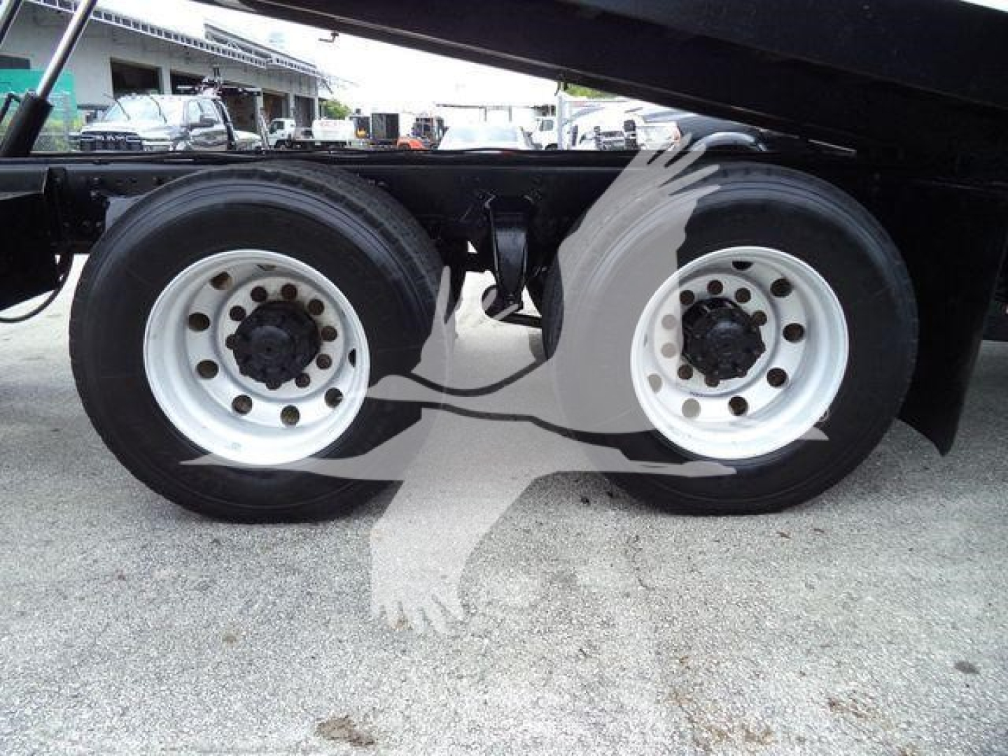Rear dual wheels of a Freightliner M2 106 roll-off truck showing white rims and tires with hub caps.