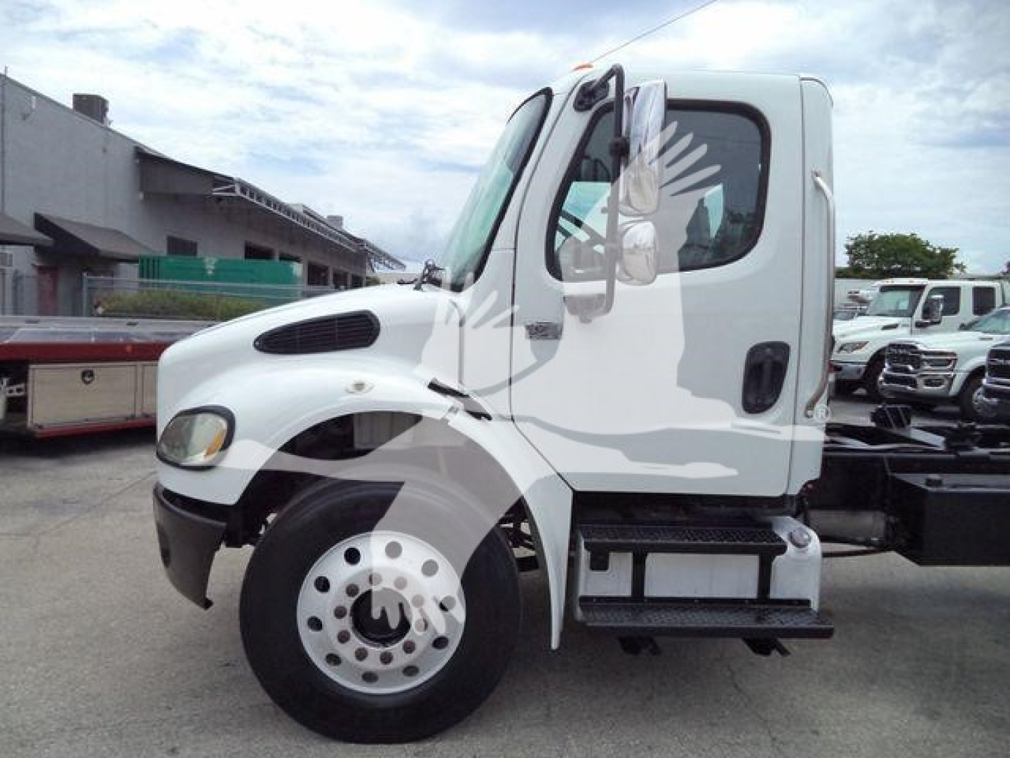 Truck cab side view of a white 2006 Freightliner M2 106 roll-off, showing front wheel, door, steps, and chassis with storage box
