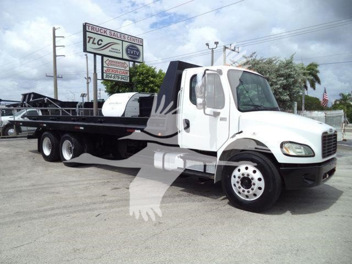 2006 Freightliner M2 106 roll-off truck side view showing flatbed with winch and dual rear axles.