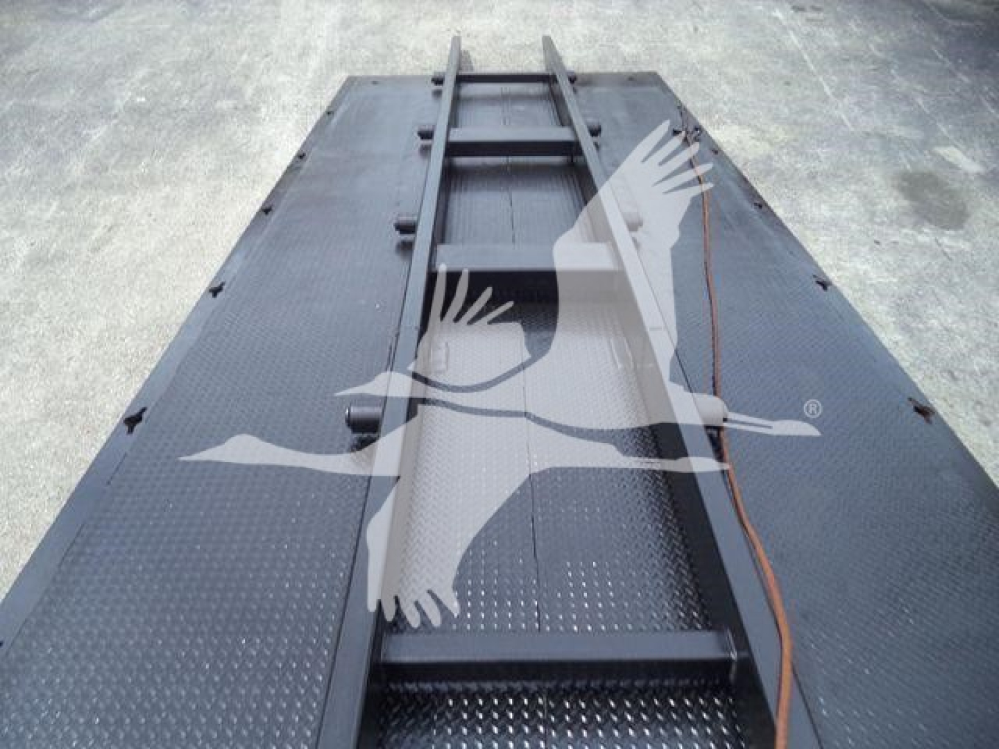 Rolloff truck bed on a Freightliner M2 106 showing the loading framework and metal diamond-plate bed with a winch cable.