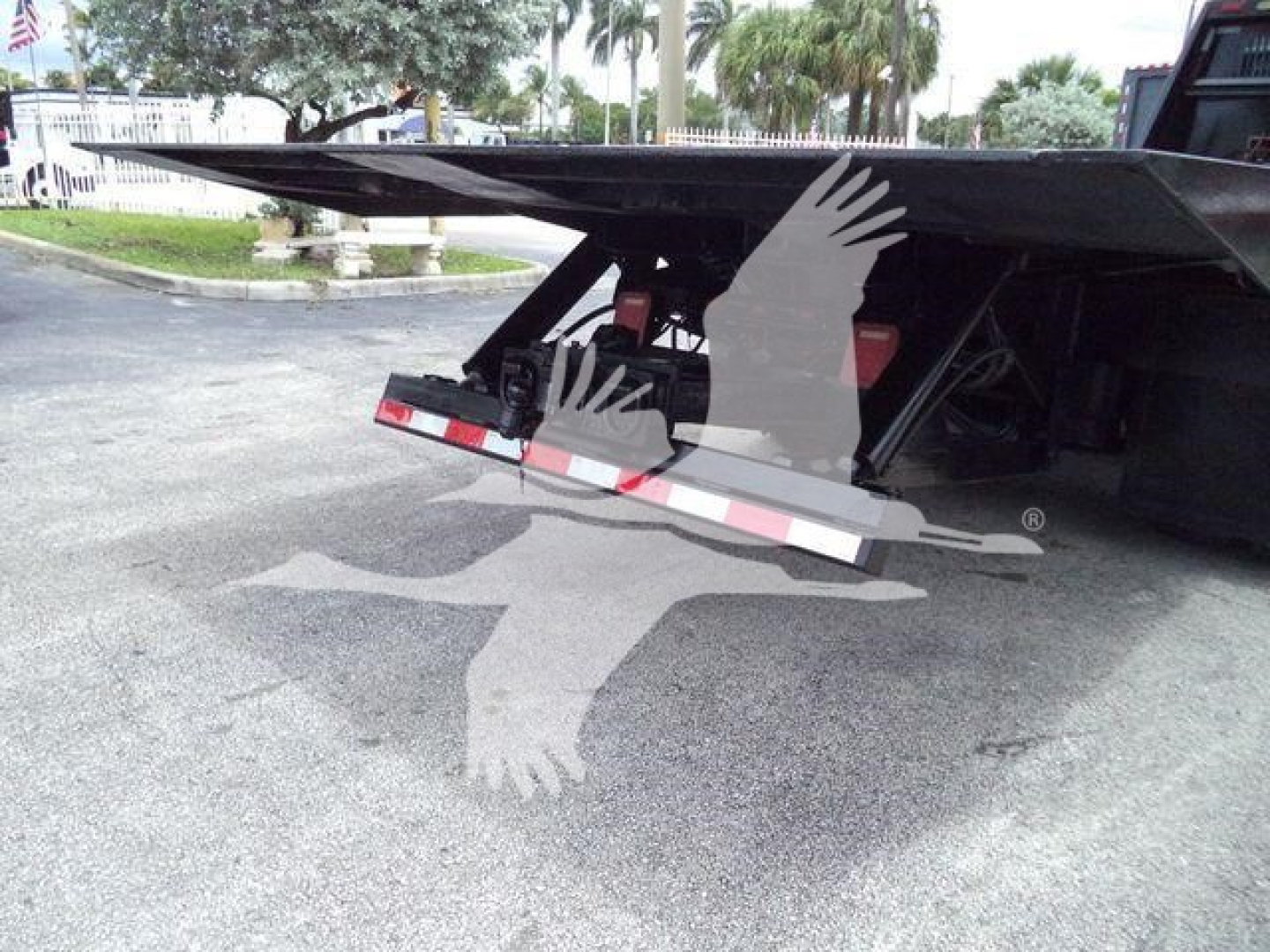 Rolloff truck bed lowered for Freightliner M2 106 showing hydraulic arms and flat decking with warning stripes.