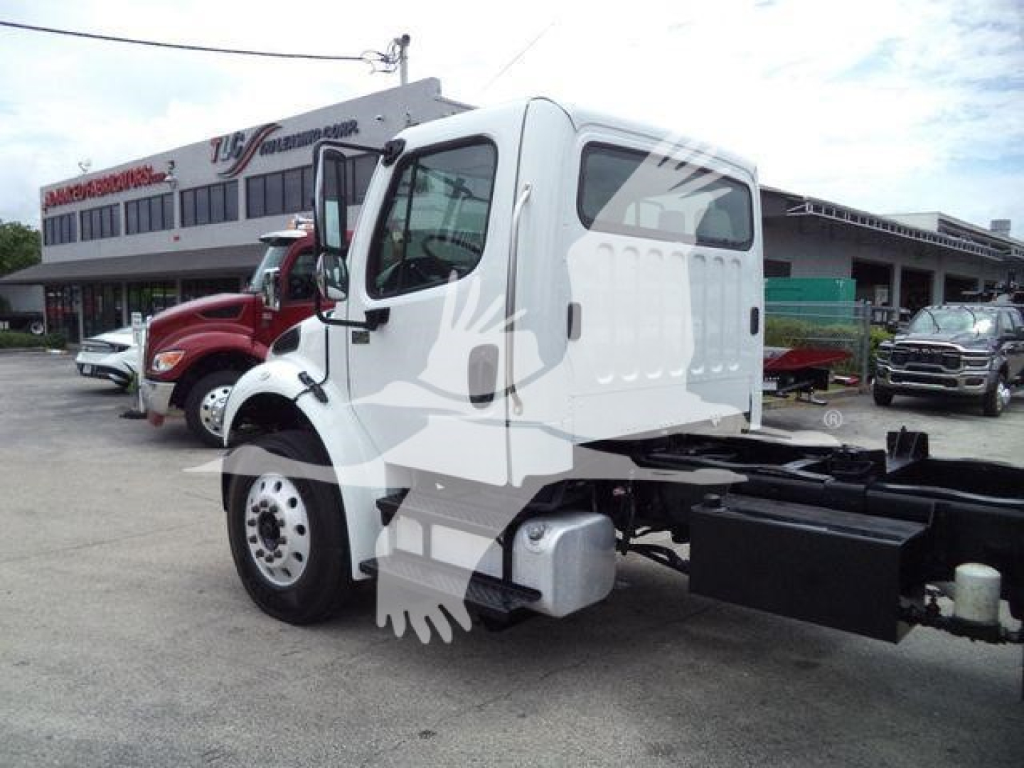 Truck cab of a 2006 Freightliner M2 106 with roll-off chassis shown from rear side, side view, dealership background.