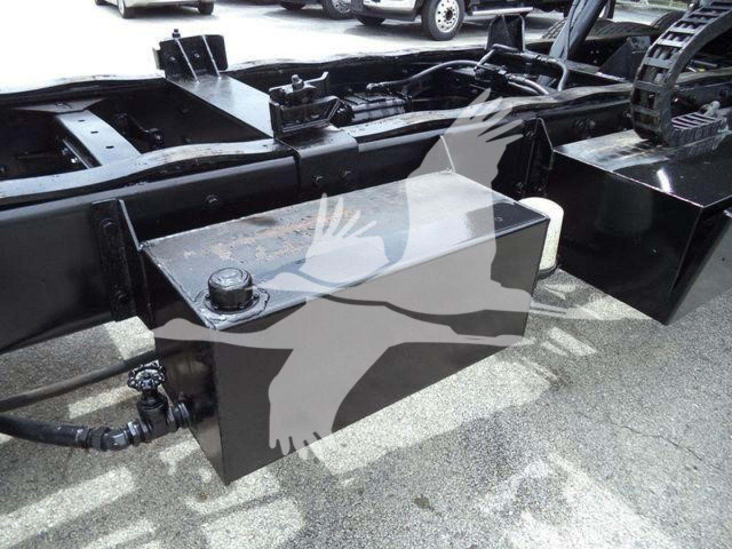 Rolloff truck chassis section showing rectangular toolbox with cap and hydraulic hose fittings.