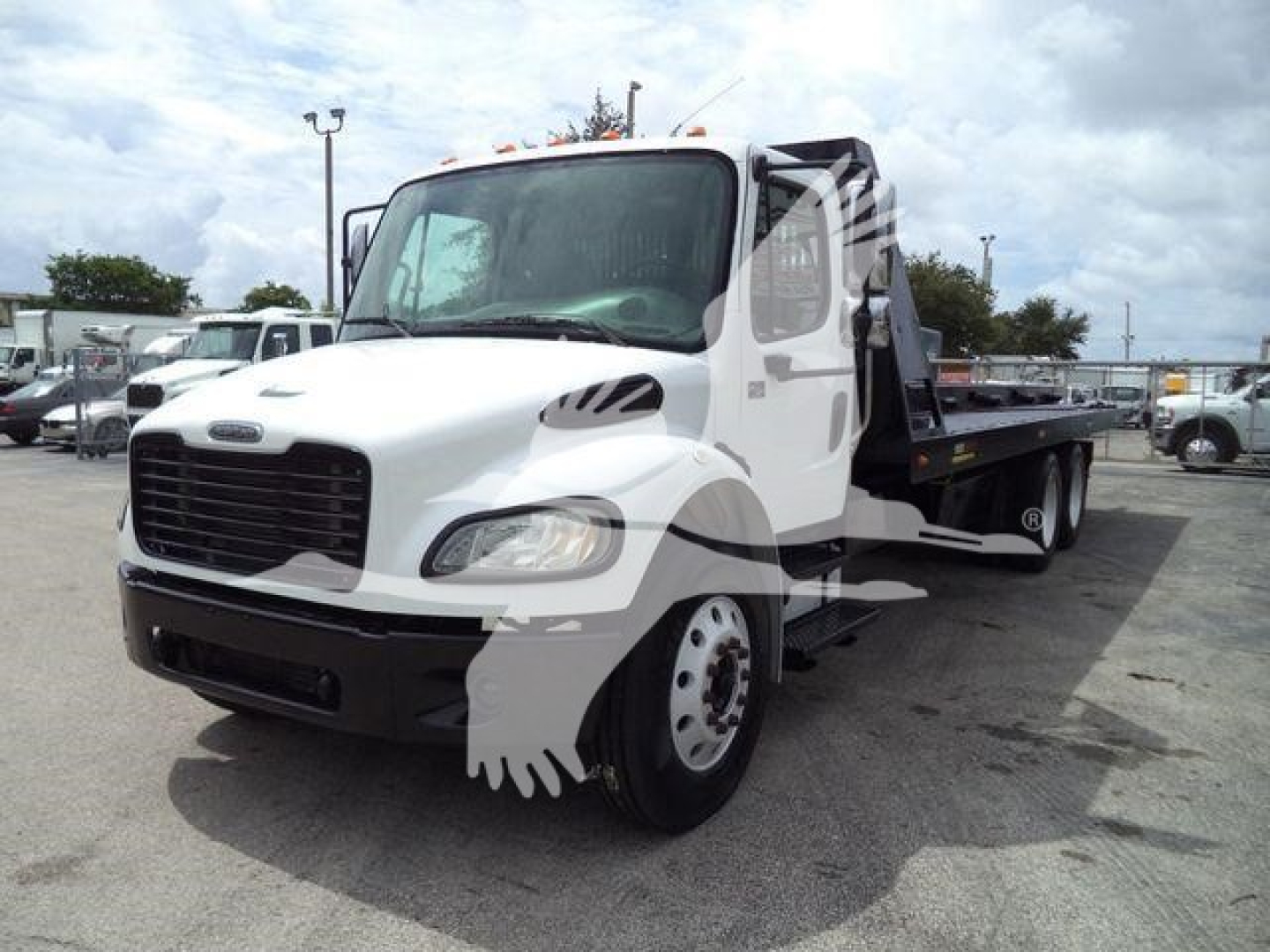2006 Freightliner M2-106 roll-off truck in white, showing front cab and flatbed/ dumping area. Visible text on grille and side not legible; overall truck with dual rear wheels and extended cab.
