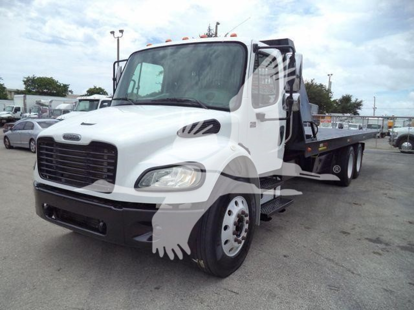 2006 Freightliner M2 106 rolloff truck front-left view with white cab and black grille, rack body on flatbed, stock number 2006M2ROLLOFF visible in a truck lot.