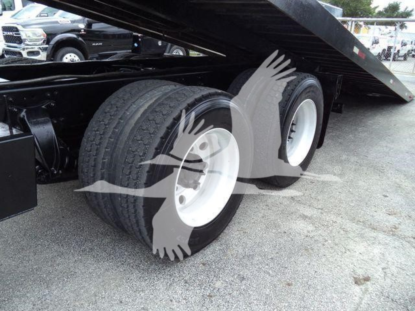 Freightliner M2 106 roll-off truck rear dual wheels and lowered bed showing tire tread and white rims.
