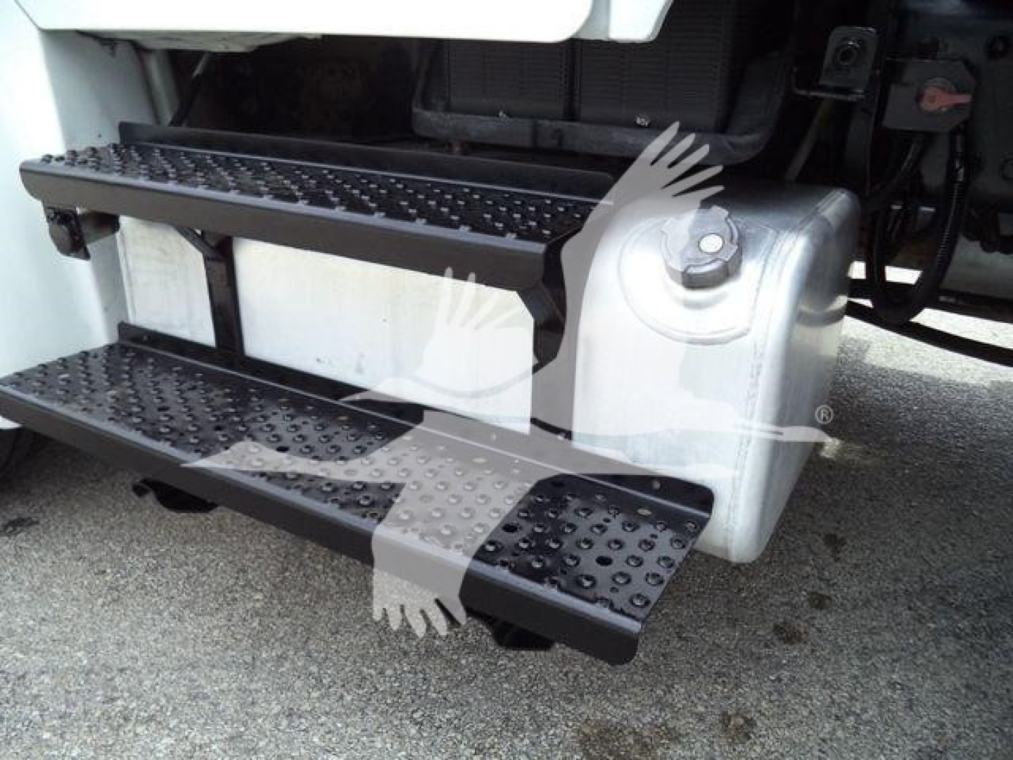 Truck side view showing fold-out metal steps attached to the Freightliner M2 106, with textured stepping surfaces and hydraulic housing nearby.