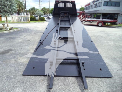 Heavy-duty roll-off truck bed in an in-service condition with a long inclined ramp and winch system visible.