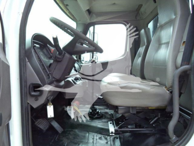 Cab interior of a 2006 Freightliner M2 106 roll-off truck showing driver seat, steering wheel, and floor area with visible controls.