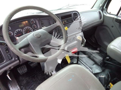 Cab interior of a Freightliner M2 106 truck showing steering wheel, dashboard, and gear shifter.