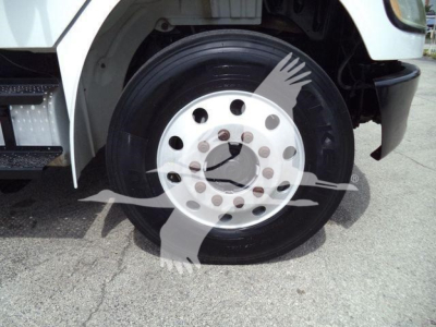 Wheel and tire on Freightliner M2 106 front, hubcap with multiple lug holes and tire in view