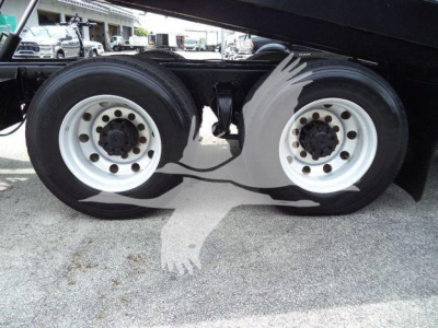 Two rear dual tires of a Freightliner M2 106 roll-off truck showing white wheels and black tires.