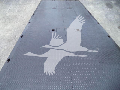 Rolloff truck bed deck showing black diamond plate surface with white gull logo and hatch/access panels.