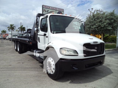 Freightliner M2 106 roll-off truck in white with black bumper and flatbed, front three-quarter view