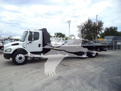 Truck showing a Freightliner M2 106 roll-off towing setup with white cab and long flatbed body, front angle view.