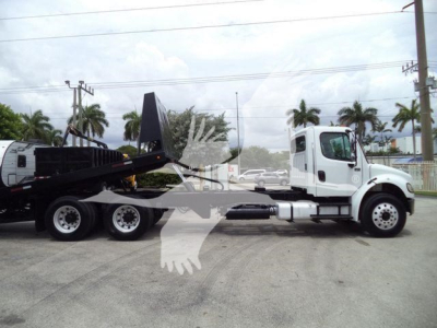 Truck: 2006 Freightliner M2 106 roll-off recovery vehicle with white cab and black trailer; side view shows roll-off hoist and hydraulic arms.