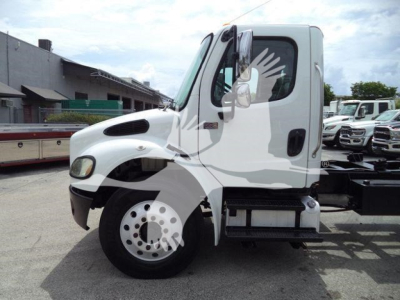 Truck cab side view showing Freightliner M2-106 with empty carrier frame and fuel tank.