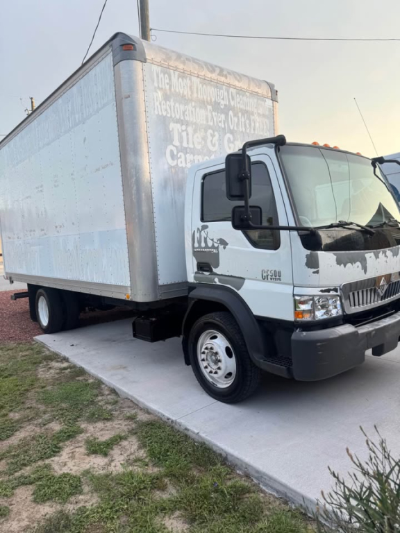 Box truck showing cargo area and cab; CF500 badge visible on front. Side of box has faded painted text; front bumper and wheel well visible.